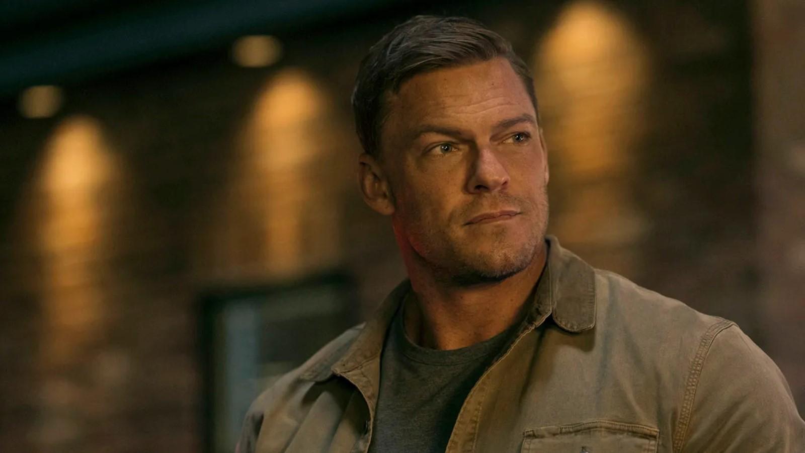 Alan Ritchson as Reacher wearing a jacket and looking off camera