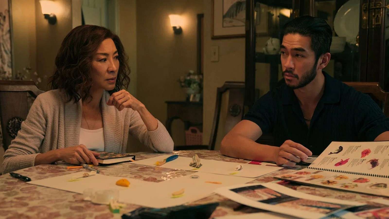Michelle Yeoh as Eileen "Mama" Sun and Justin Chien as Charles Sun sitting at the table with papers in front of them