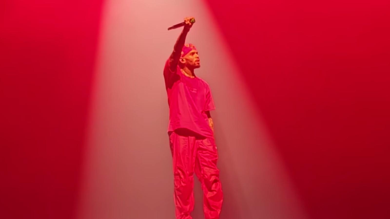Chris Brown performing in red light on a stage in London