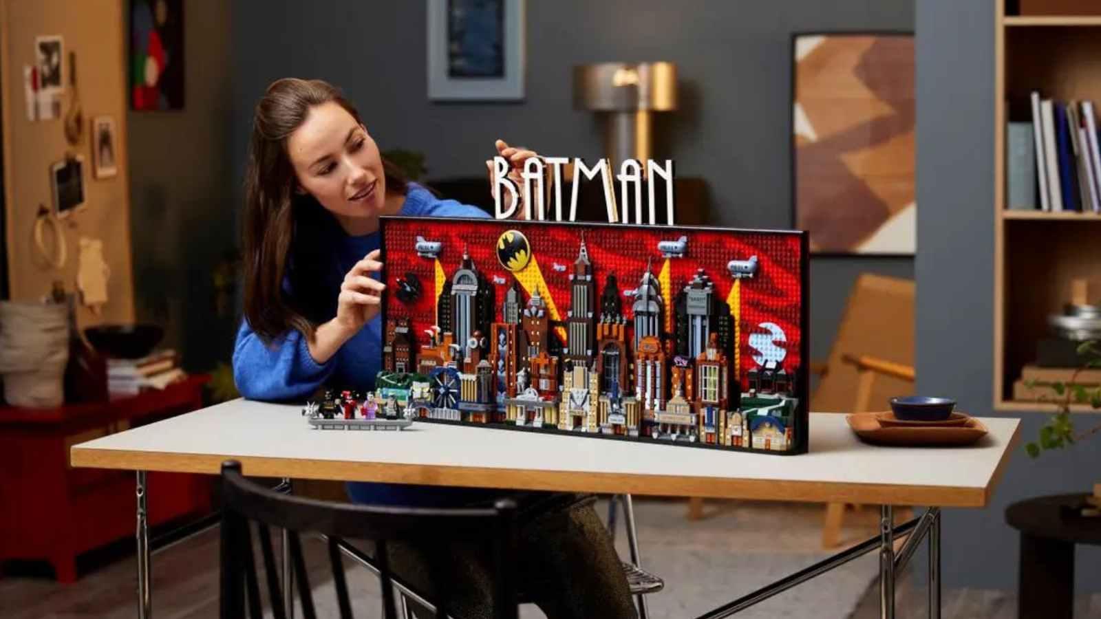 An adult with their LEGO Batman Gotham City set, which will be released in April 2024