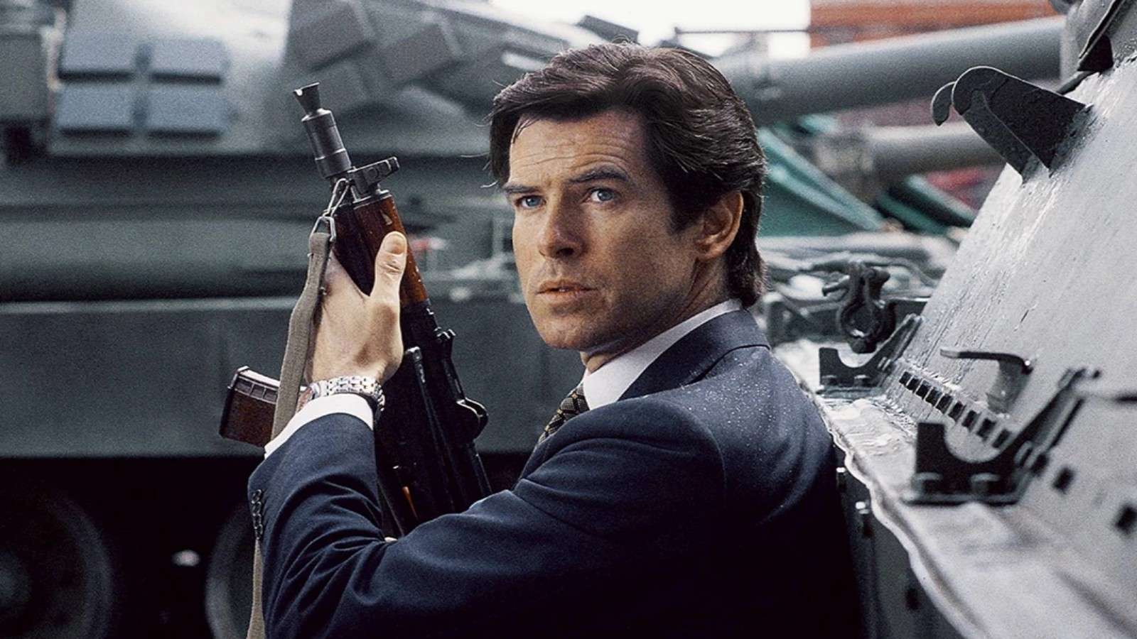 Pierce Brosnan holding a gun, on a tank, as James Bond.