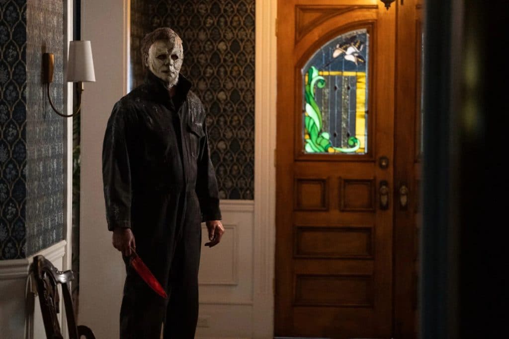 Michael Myers in Halloween Ends, standing in a house and holding a knife