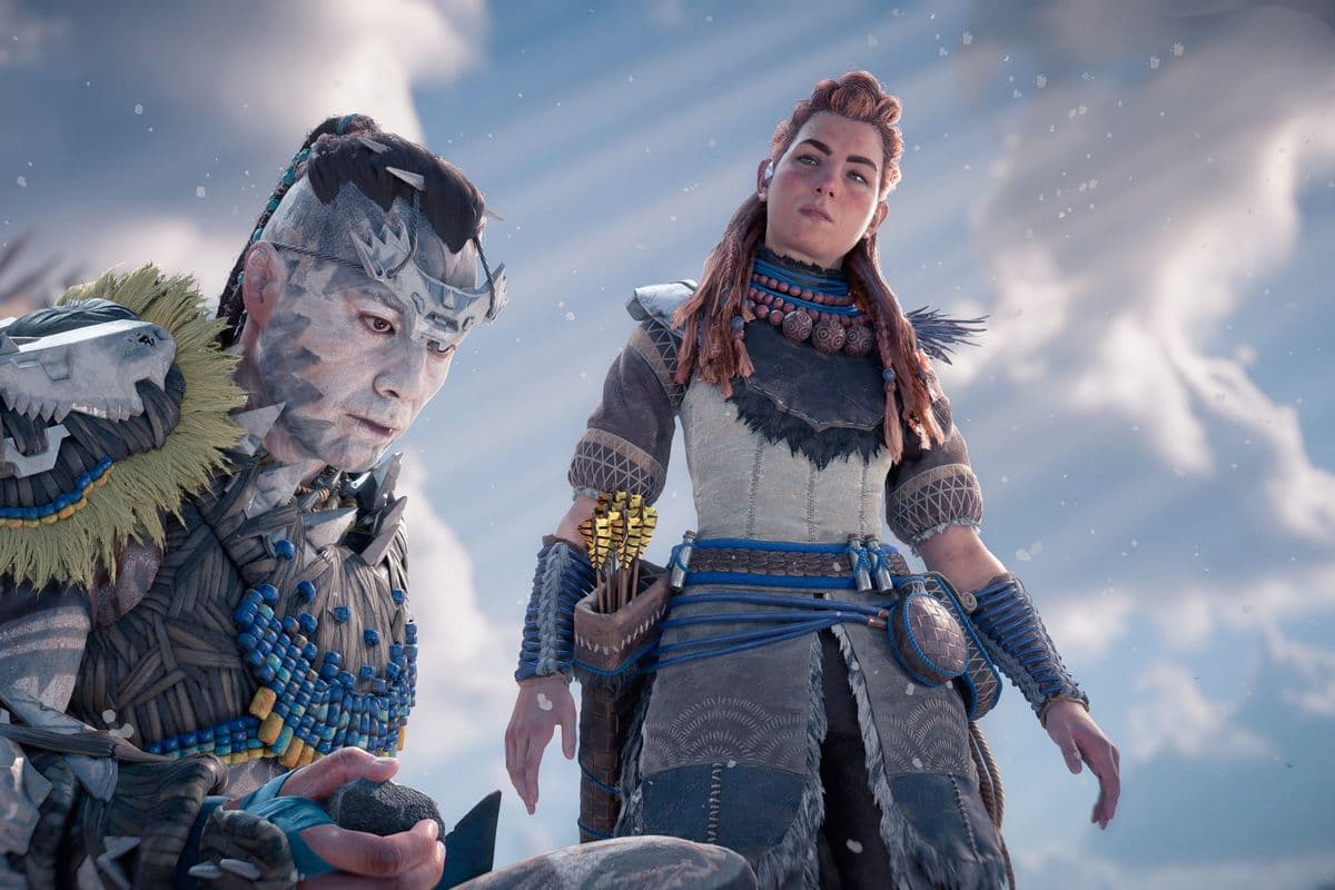 Aloy in Horizon Forbidden West. She looks over a young man in white and blue face paint.