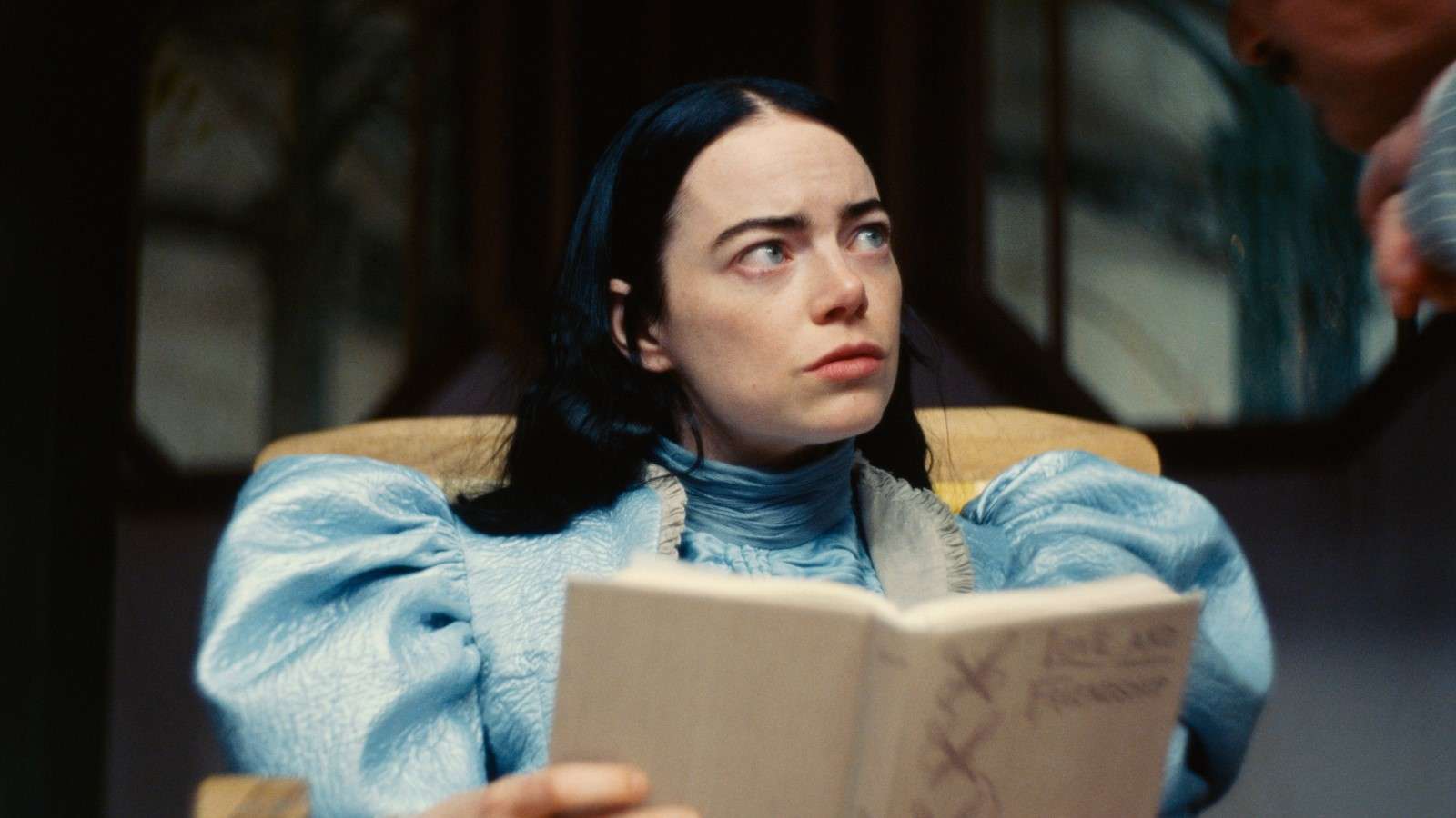 Emma Stone as Bella Baxter in Poor Things, reading a book