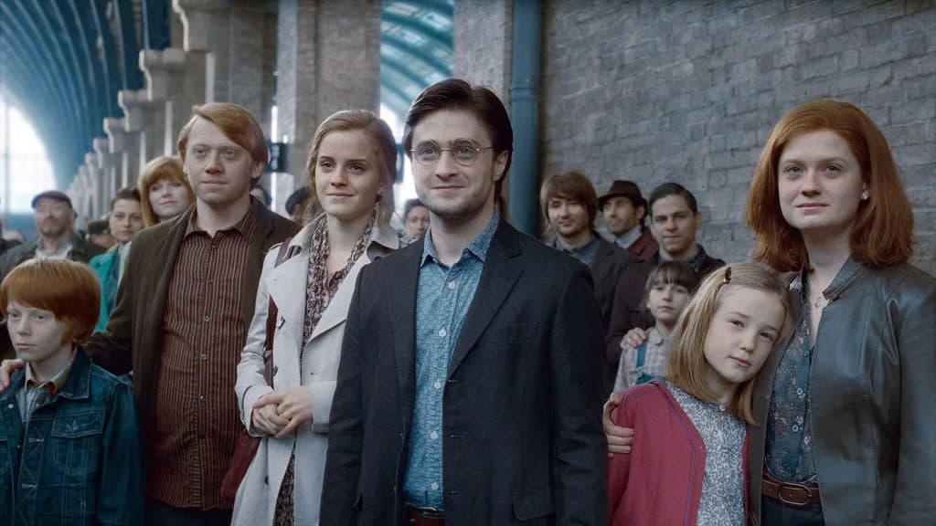 Adult Ron, Hermione, Harry, and Ginny at the train station watching their children leave