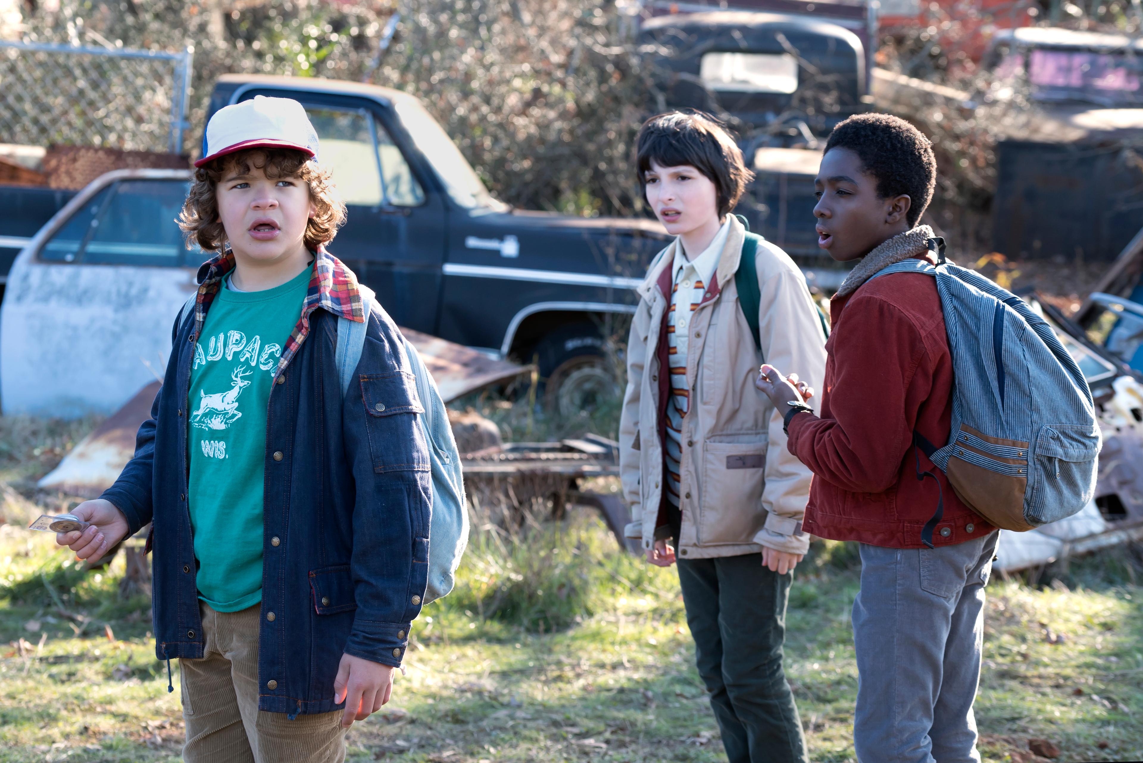 Dustin, Mike, Lucas, and Caleb stand in a field in Stranger Things Season 1.