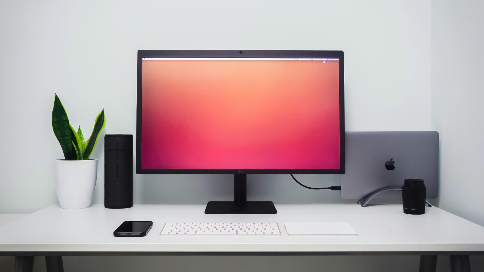 A monitor on a table with Apple Mac next to it