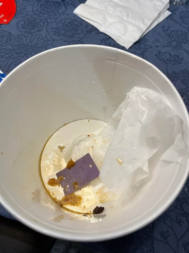 A photo of an empty KFC bucket with a purple card inside.