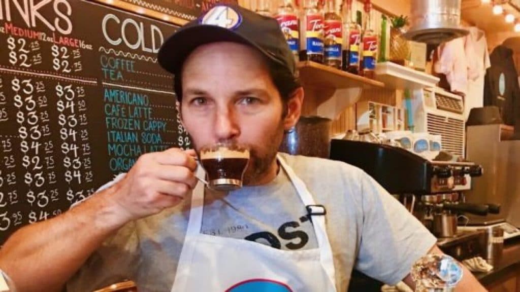 Paul Rudd drinking a coffee in a Samuel's Sweet Shop uniform