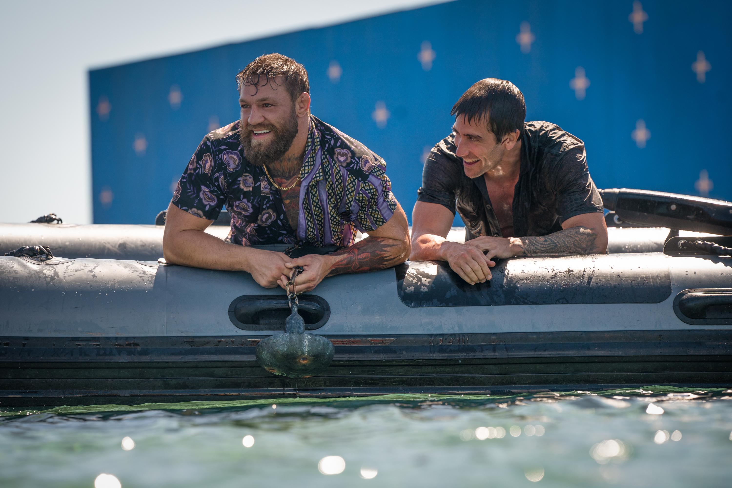 Jake Gyllenhaal and Conor McGregor filming Road House in the Dominican Republic. They are in a dingy boat, laughing.