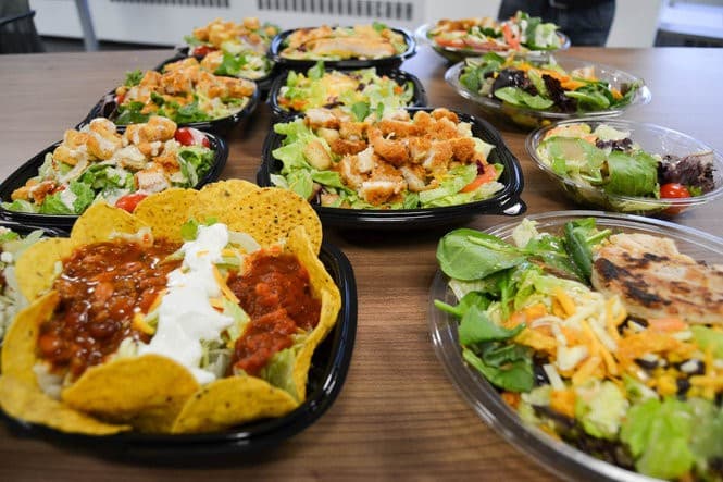 A photo of lots of fast food salads on a table