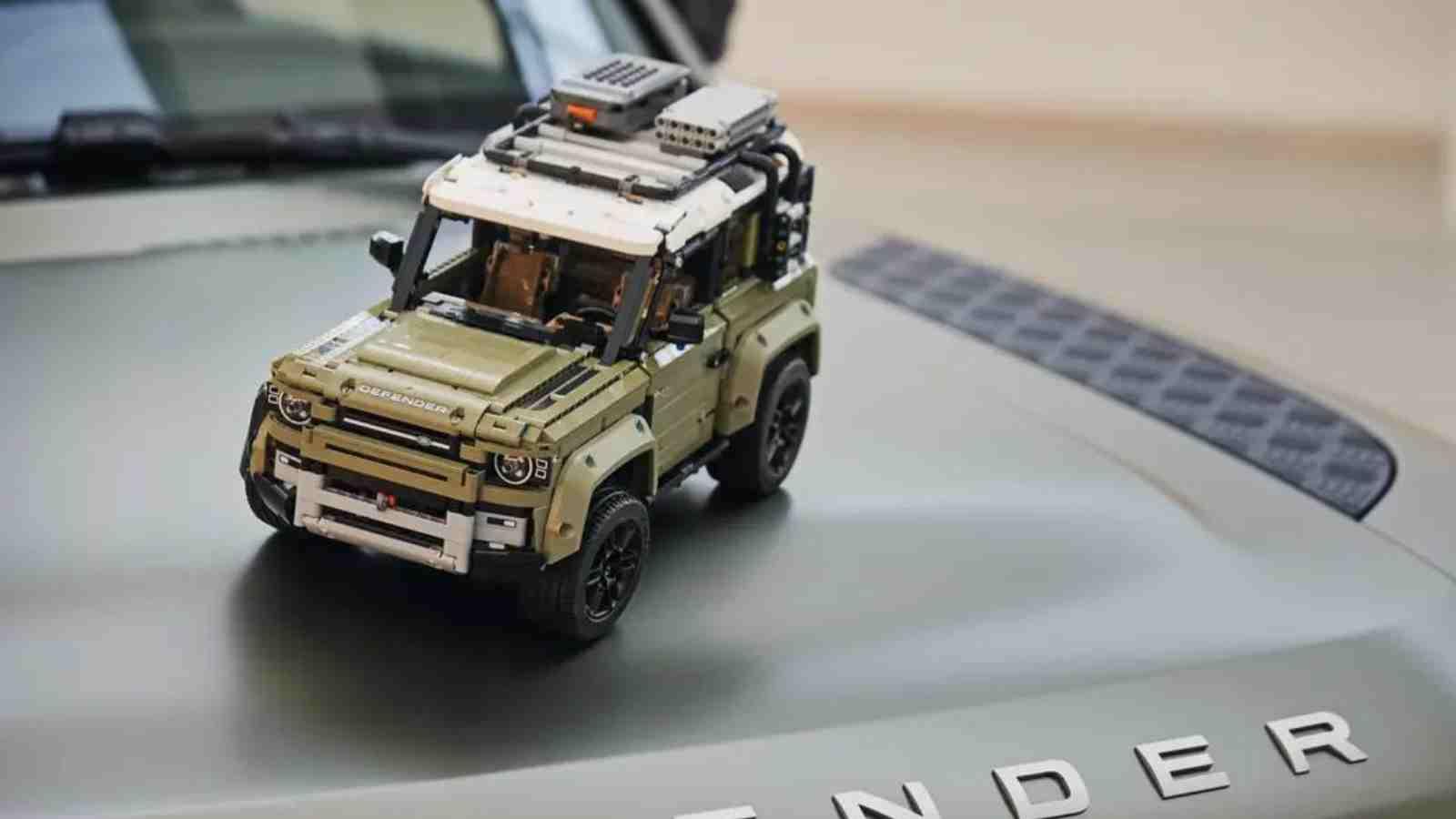 The LEGO Technic Land Rover Defender on the hood of the real-life Defender