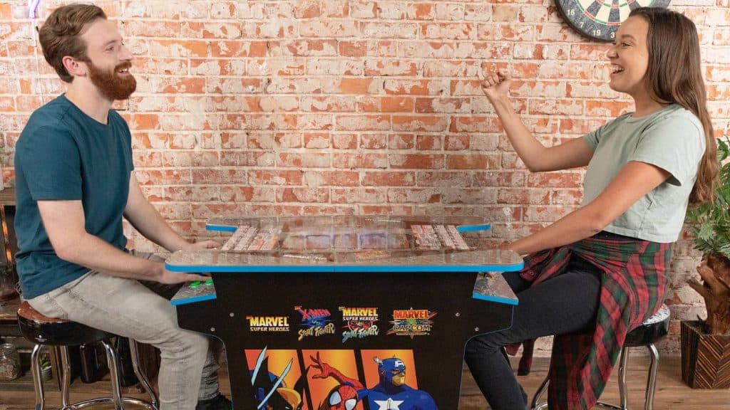 Image of two people playing the Marvel vs Capcom arcade table.
