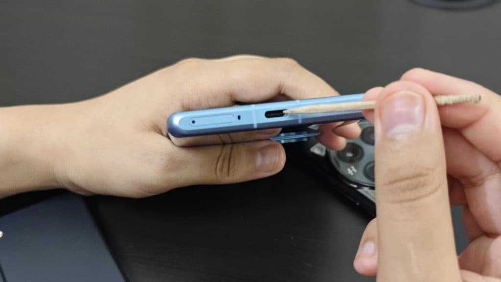 Image showing a smartphone's charging port and hands carrying a toothpick.
