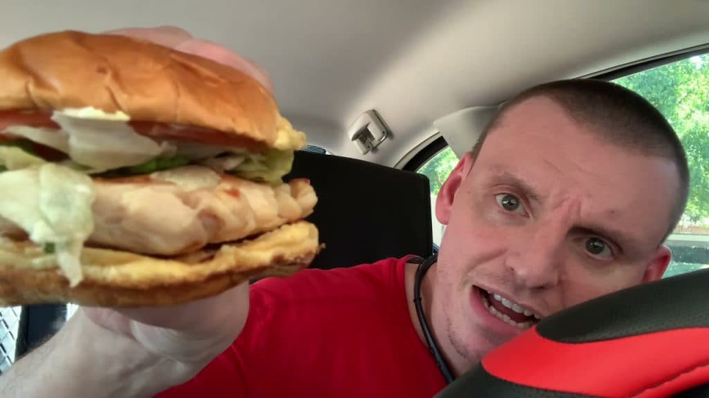 A man eating Sonic's grilled chicken burger