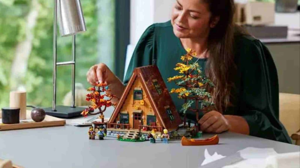 An adult with their LEGO Ideas A-Frame Cabin