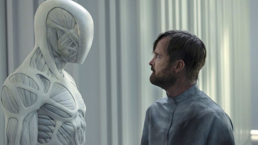 Shows to watch if you like Fallout: Aaron Paul as Caleb in Westworld, standing in front of a white muscular figure