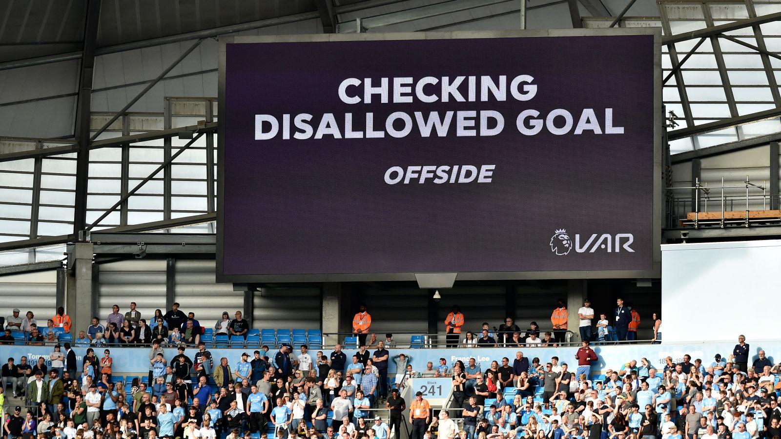 A stadium screen showing the words 'VAR: Checking Disallowed Goal, Offside."
