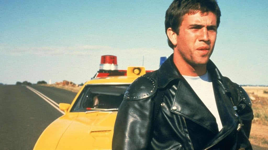 Mad Max standing in front of his police car.