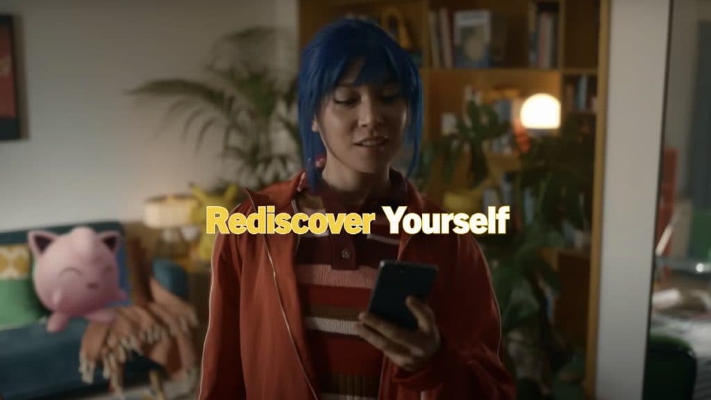 Женщина с синими волосами стоит в гостиной с текстом «Открой себя заново».