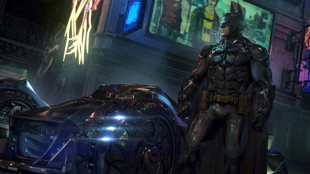 Batman stands next to the Batmobile in Arkham Knight