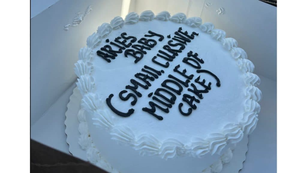 A cake saying "Aries Baby (small, cursive, middle of cake.)