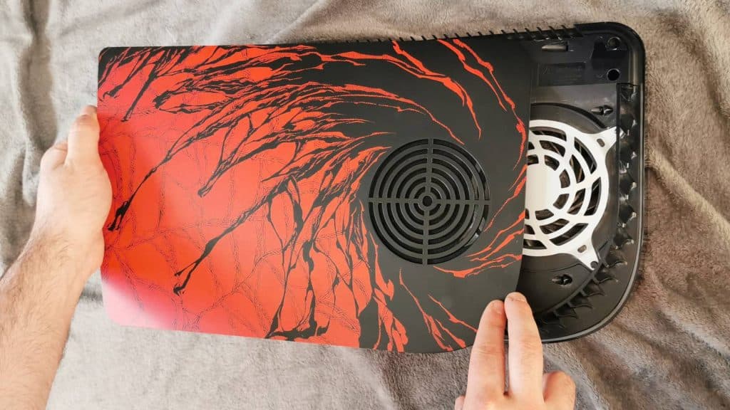Image of the Dbrand Arachnoplates PS5 cover being attached to a launch PS5 model.