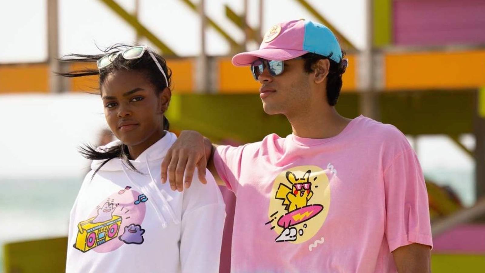 Two models are shown on a beach wearing pastel-colored Pokemon clothing
