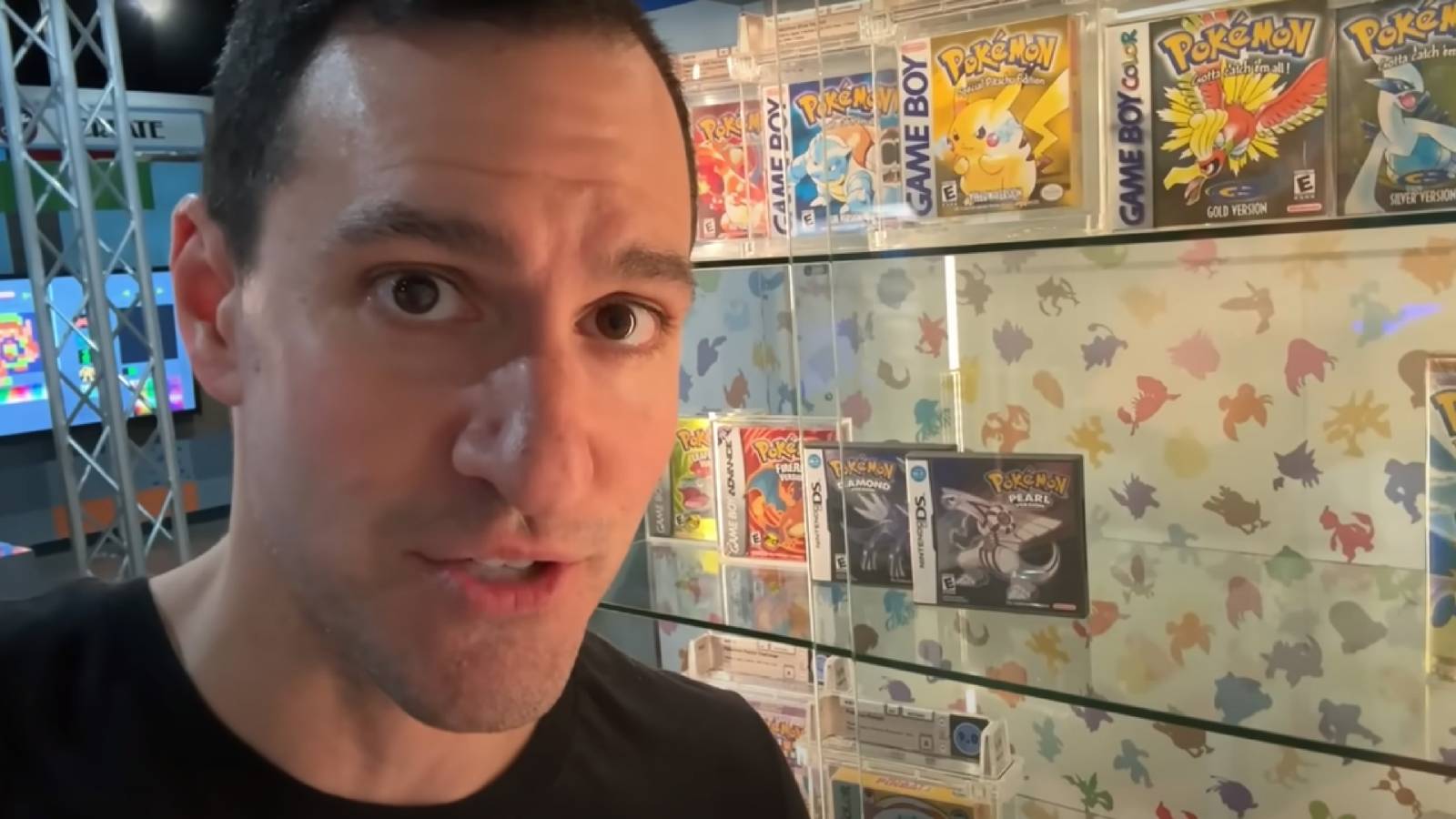 YouTube content creator Leonhart stands in front of a glass cabinet filled with vintage Pokemon games in their boxes