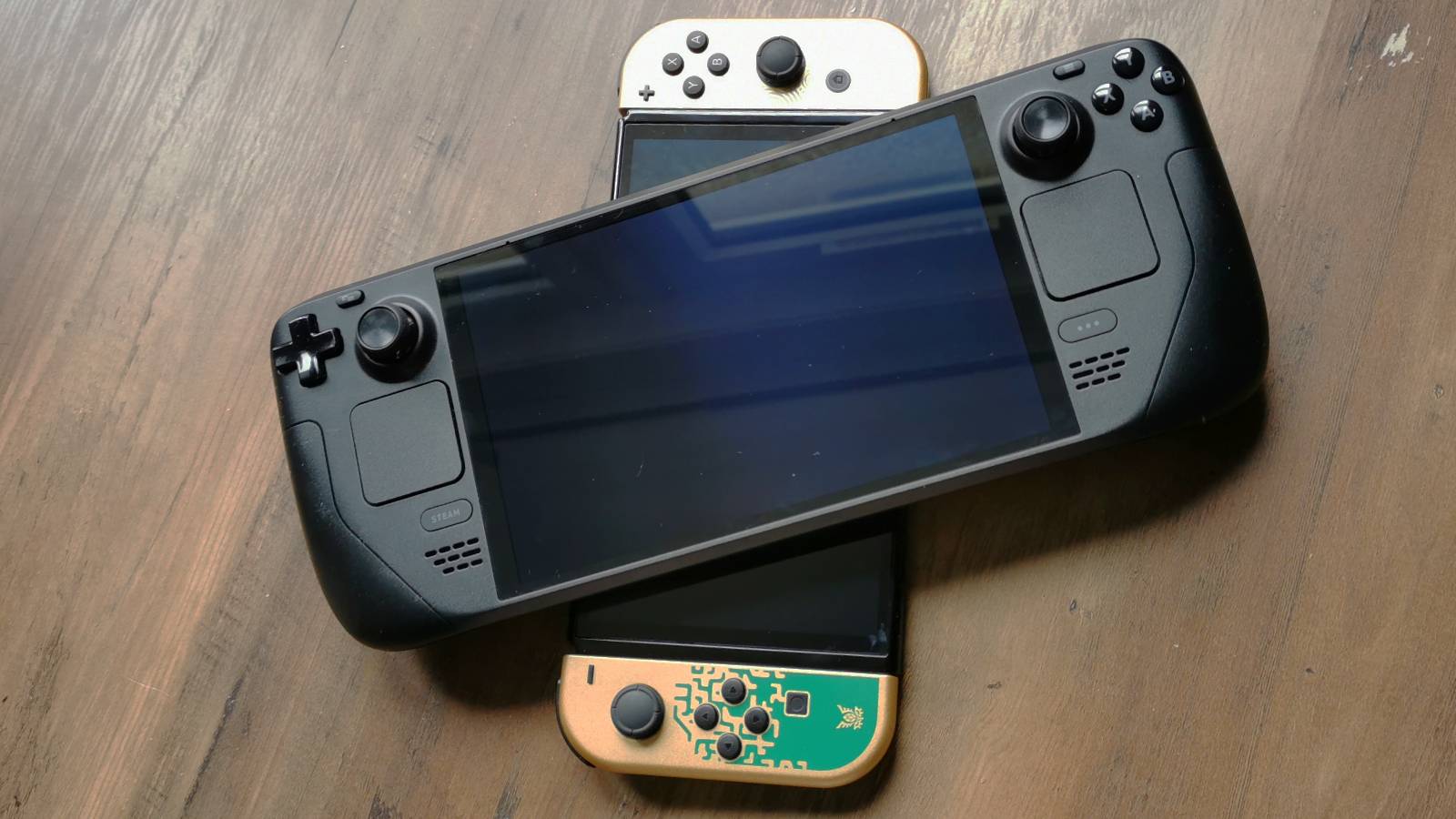 Image of a Steam Deck OLED sitting on top of The Legend of Zelda: Teaars of the Kingdom edition Switch OLED.