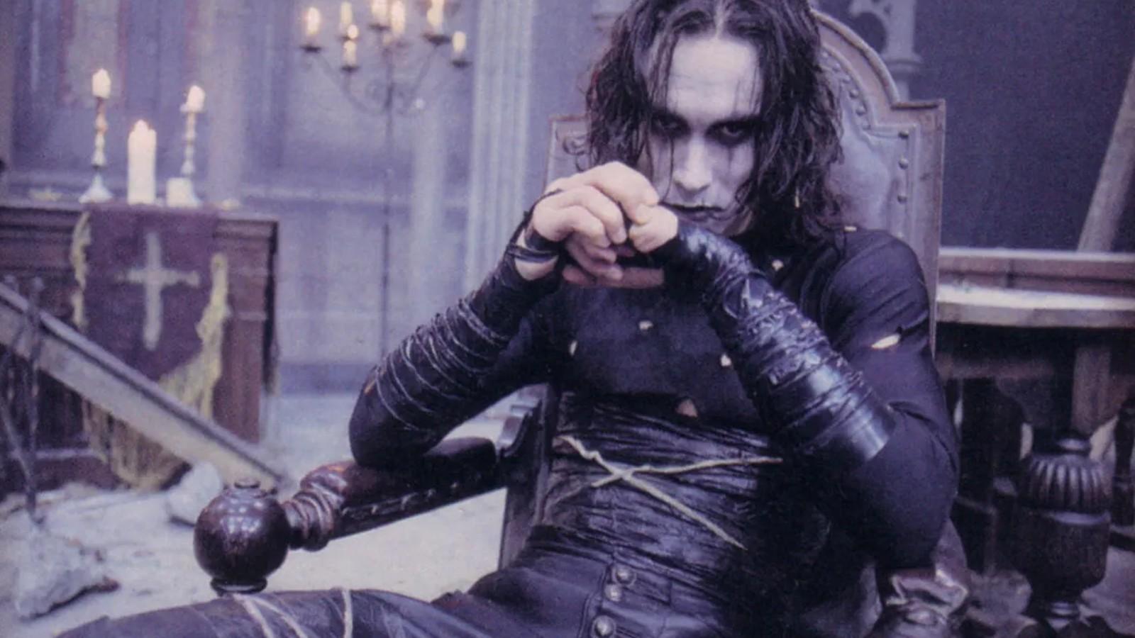 Brandon Lee sitting in a chair in goth makeup in The Crow.