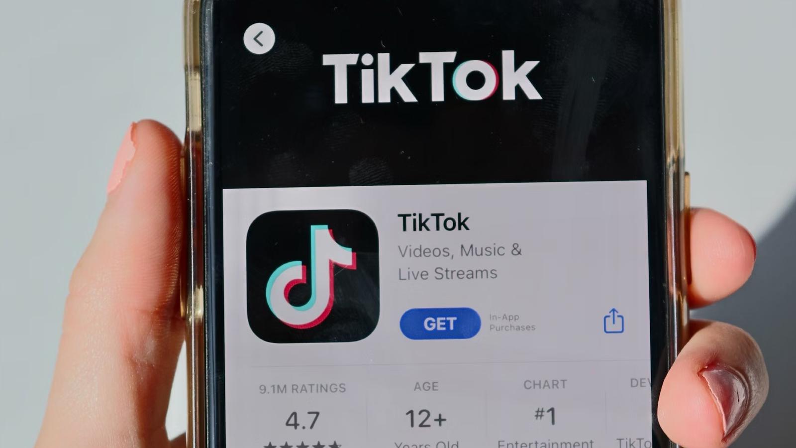 Hand holding phone with TikTok open in the app store.