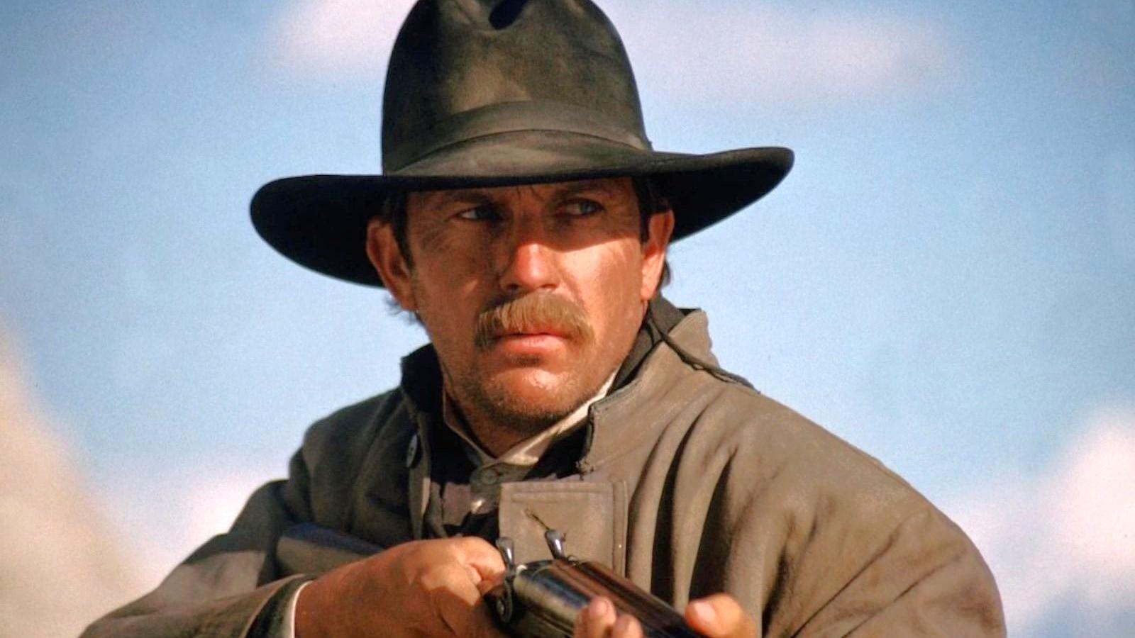 Kevin Costner wearing a cowboy hat and holding a gun