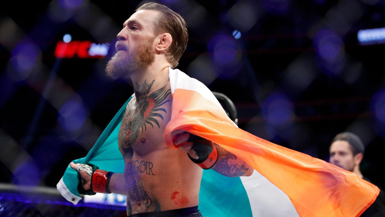 Conor McGregor drapes an Irish flag around his shoulders in the Octagon